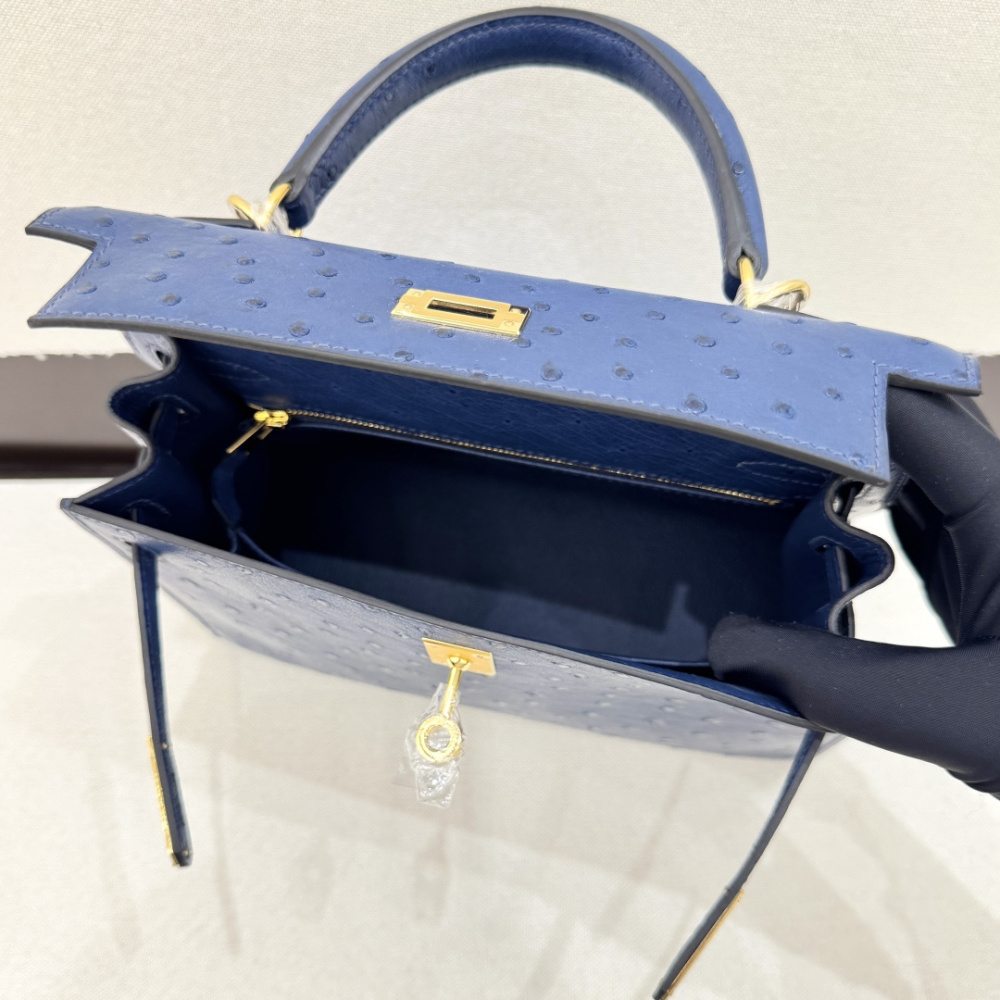 The Hermès Kelly 25 handbag in ostrich leather—rendered in a deep marine blue (gemstone blue / midnight blue) and accented with gold hardware—stands as a quintessential example of understated luxury among Hermès' exotic skins.