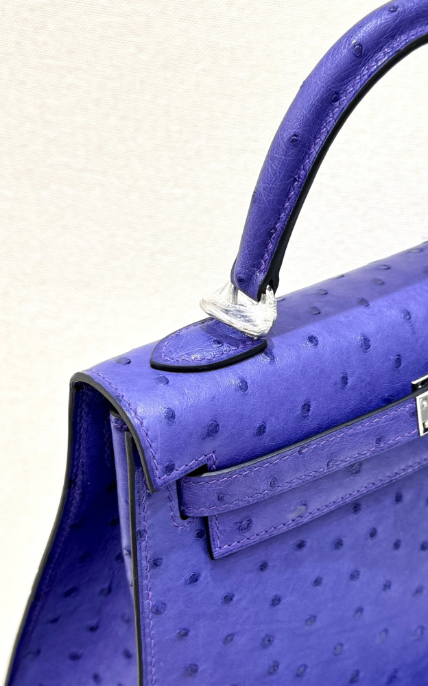 The Hermès Kelly 25 handbag in ostrich leather—featuring a striking electric purple (Iris/Lavender) hue paired with silver hardware—stands as an iconic representative among Hermès' exotic skins, distinguished by its exceptional individuality and artistic