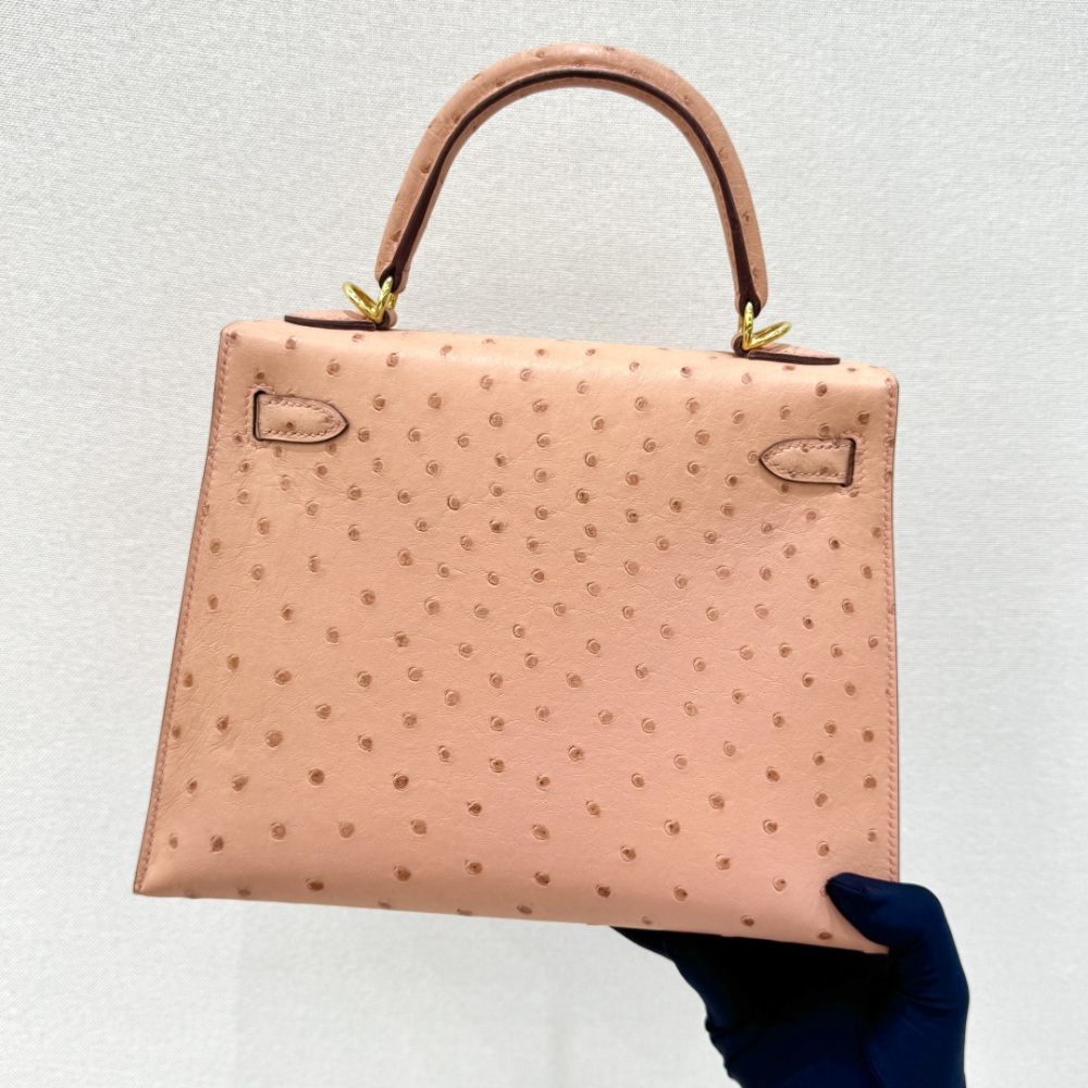 The Hermès Kelly 25 handbag in Ostrich leather—featuring a soft "Sakura Pink" hue (also known as "Nude Pink" or "Baby Pink") paired with gold hardware—is a highly sought-after model among Hermès exotic skins, perfectly blending a youthful, girlish charm w