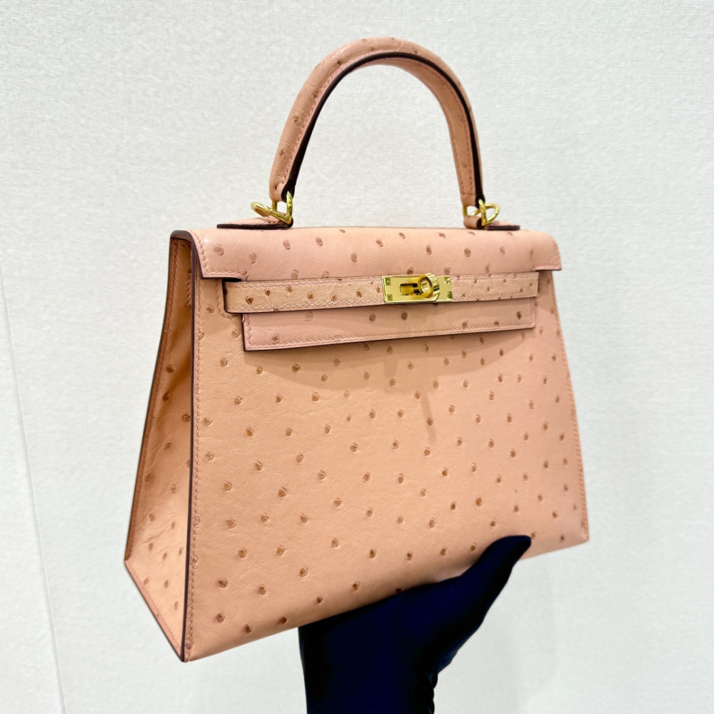 The Hermès Kelly 25 handbag in Ostrich leather—featuring a soft "Sakura Pink" hue (also known as "Nude Pink" or "Baby Pink") paired with gold hardware—is a highly sought-after model among Hermès exotic skins, perfectly blending a youthful, girlish charm w