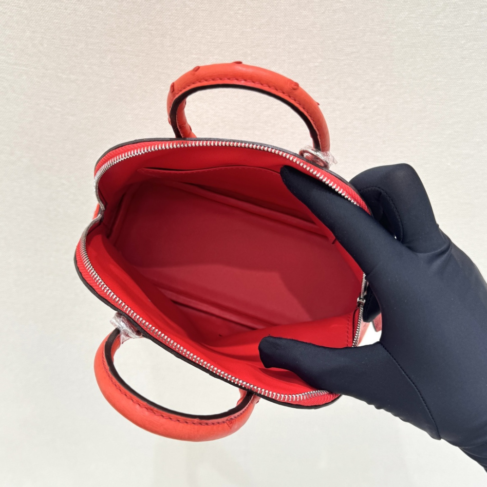 The Hermès Mini Bolide handbag in ostrich leather—featuring a striking Tomato Red (orange-red) hue paired with silver hardware—is a vibrant and highly sought-after piece within the brand's rare skins collection.