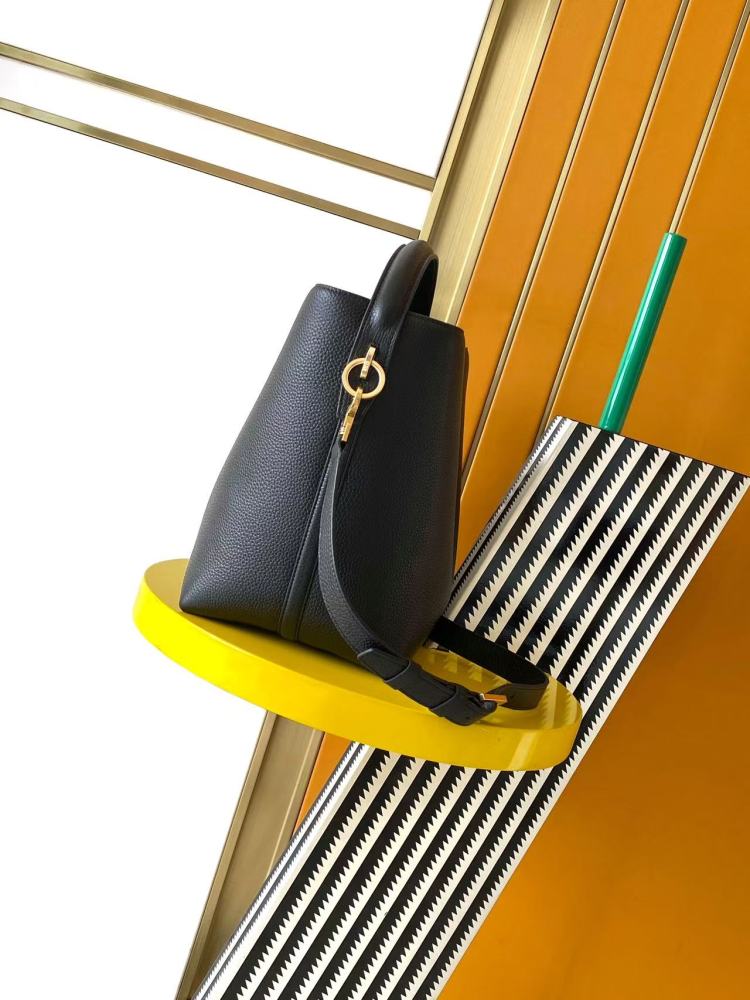 This is a bucket bag from Yves Saint Laurent (YSL), crafted in black grained leather with a gold-tone YSL logo hardware. It comes with a detachable pouch and strap, suitable for both hand-held and crossbody wear.