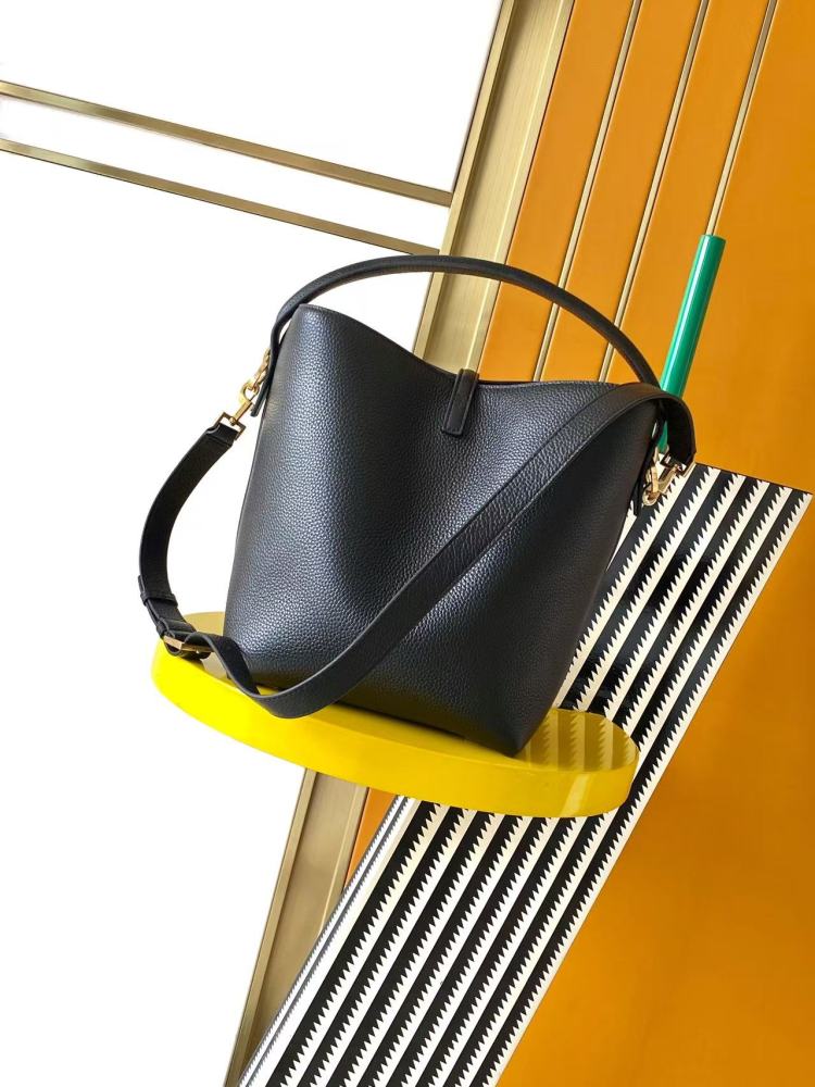 This is a bucket bag from Yves Saint Laurent (YSL), crafted in black grained leather with a gold-tone YSL logo hardware. It comes with a detachable pouch and strap, suitable for both hand-held and crossbody wear.