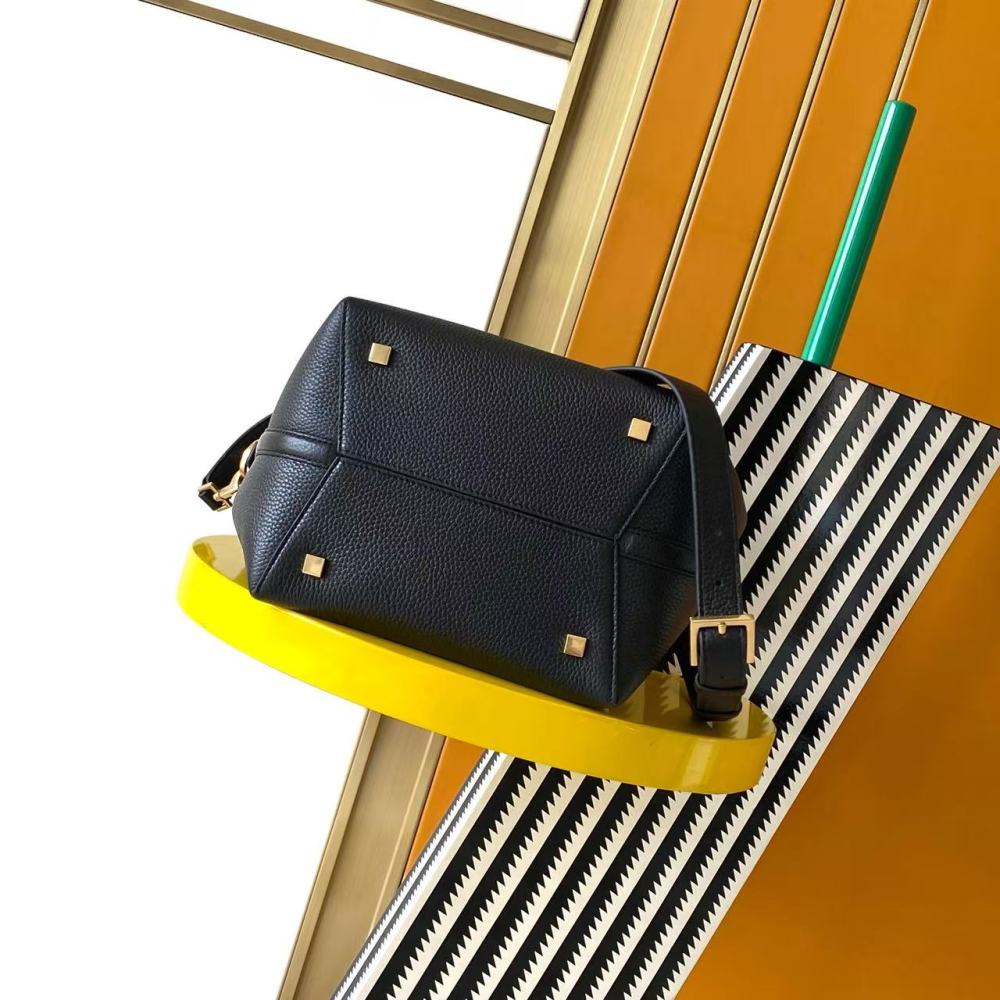 This is a bucket bag from Yves Saint Laurent (YSL), crafted in black grained leather with a gold-tone YSL logo hardware. It comes with a detachable pouch and strap, suitable for both hand-held and crossbody wear.