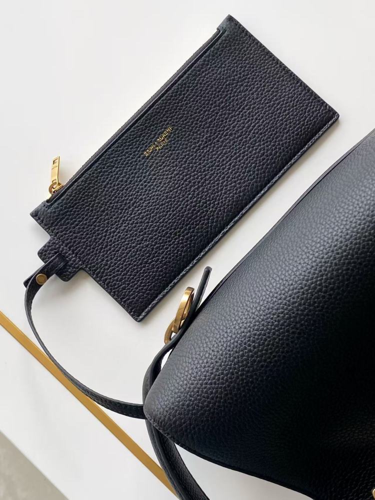 This is a bucket bag from Yves Saint Laurent (YSL), crafted in black grained leather with a gold-tone YSL logo hardware. It comes with a detachable pouch and strap, suitable for both hand-held and crossbody wear.