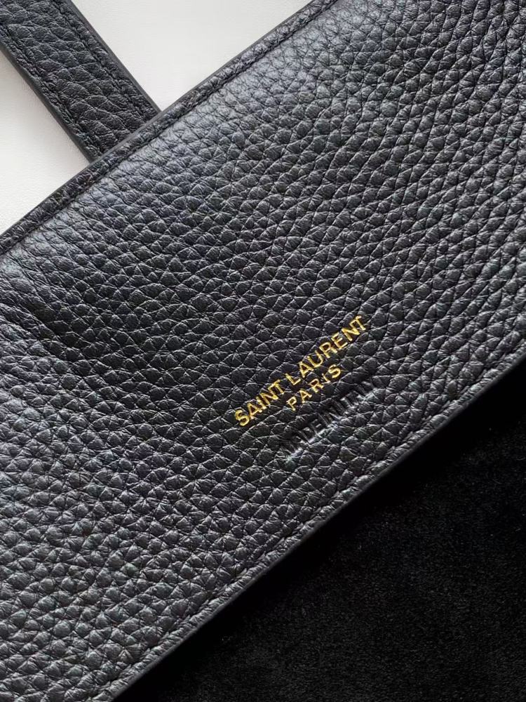 This is a bucket bag from Yves Saint Laurent (YSL), crafted in black grained leather with a gold-tone YSL logo hardware. It comes with a detachable pouch and strap, suitable for both hand-held and crossbody wear.