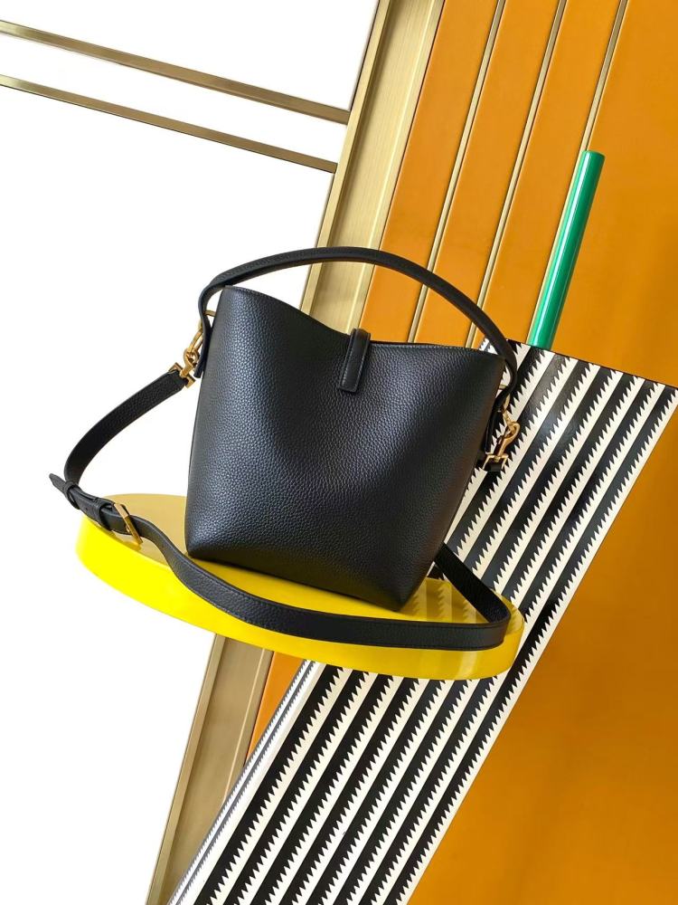 This is a small bucket bag from Yves Saint Laurent (YSL), crafted in black grained leather with a gold-tone YSL logo hardware. It comes with a detachable strap, suitable for both hand-held and crossbody wear.
