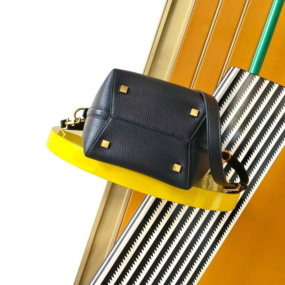 This is a small bucket bag from Yves Saint Laurent (YSL), crafted in black grained leather with a gold-tone YSL logo hardware. It comes with a detachable strap, suitable for both hand-held and crossbody wear.