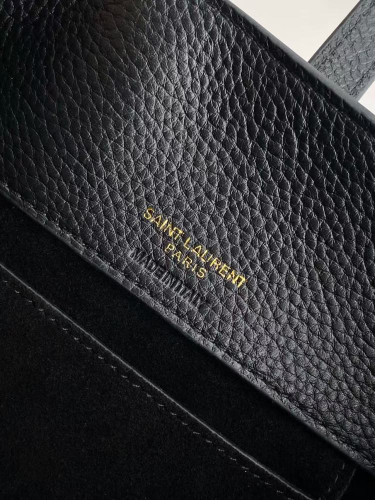 This is a small bucket bag from Yves Saint Laurent (YSL), crafted in black grained leather with a gold-tone YSL logo hardware. It comes with a detachable strap, suitable for both hand-held and crossbody wear.