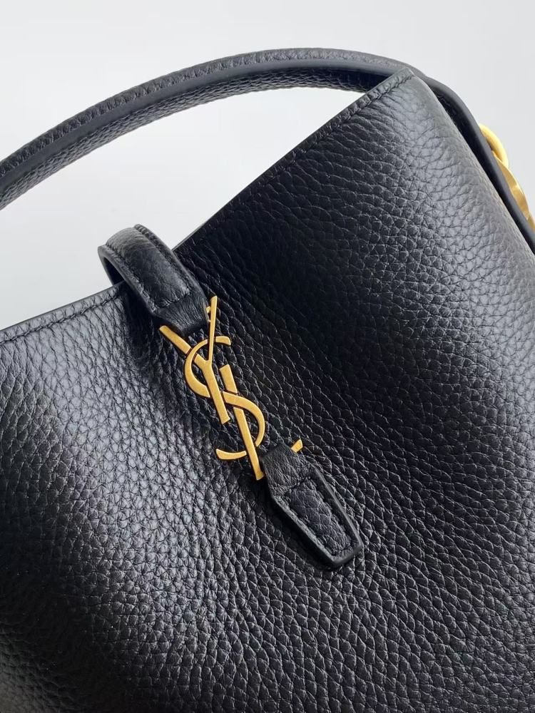 This is a bucket bag from Yves Saint Laurent (YSL), crafted in black grained leather. The front of the bag is adorned with a prominent gold-tone YSL logo hardware. It comes with a detachable short top handle and a long crossbody strap, allowing for multip