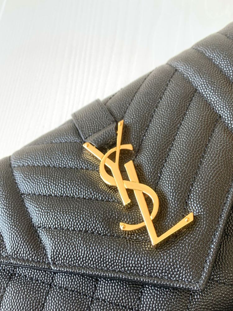 This is a quilted envelope bag from YSL, crafted in black caviar leather with a gold-tone logo and metal chain strap, suitable for shoulder or crossbody wear.