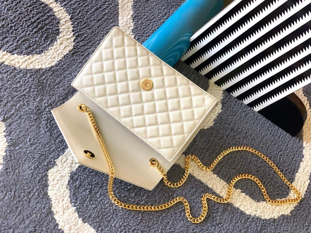 This is a quilted envelope bag from YSL, crafted in off-white caviar leather with a gold-tone logo and metal chain strap, suitable for shoulder or crossbody wear.
