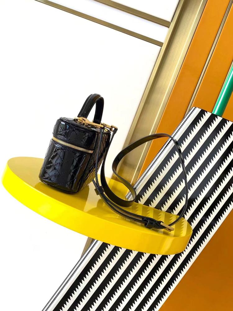 This is a quilted cosmetic bag from YSL, crafted in black patent leather with a gold-tone logo and detachable strap, suitable for hand-held or shoulder wear.