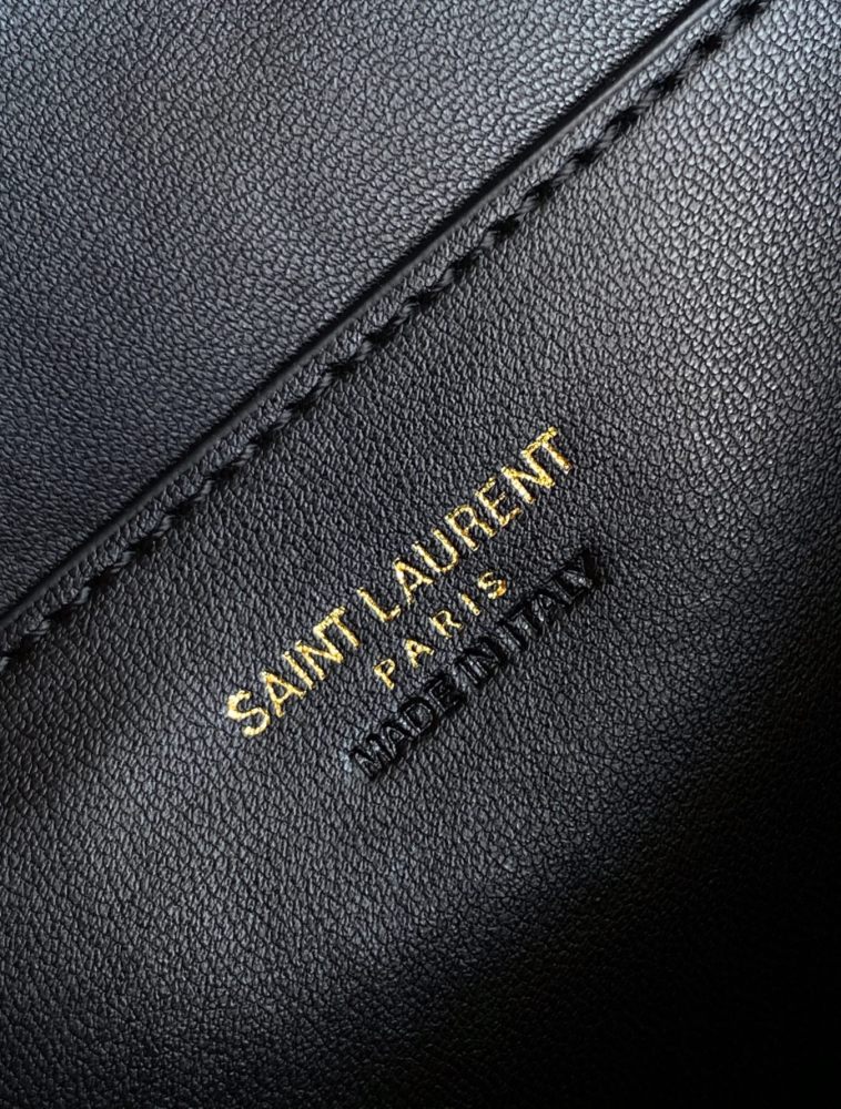 This is a quilted cosmetic bag from YSL, crafted in off-white grained leather with a gold-tone logo and detachable strap, suitable for hand-held or shoulder wear.