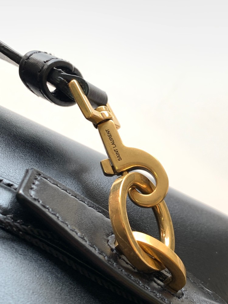 This is a classic shoulder bag from the YSL (Yves Saint Laurent) Kate collection. It is crafted from black pebbled leather, paired with the iconic gold-tone YSL logo and a gold-tone metal chain.