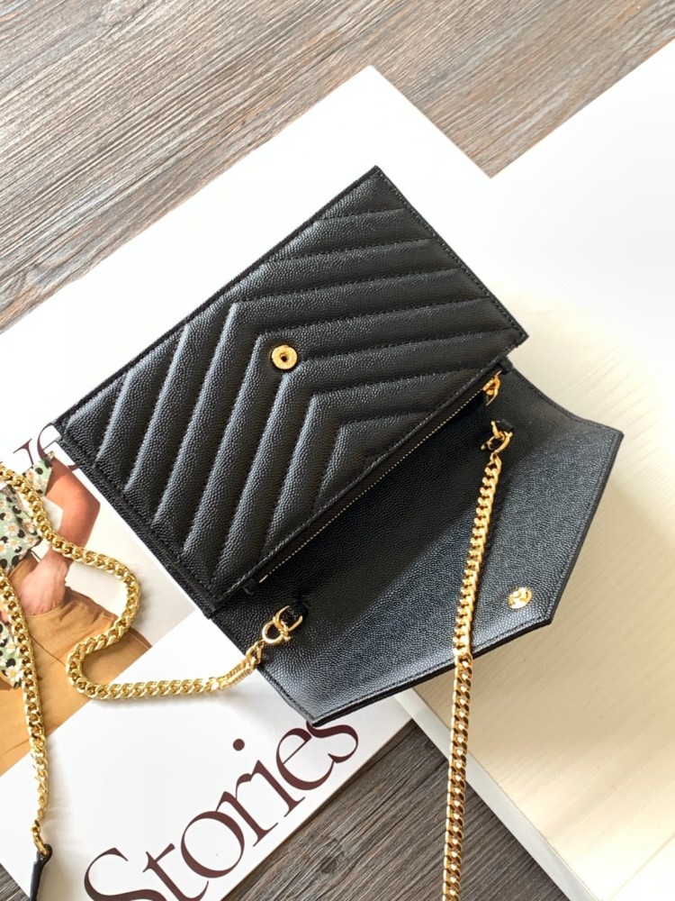 This is the YSL Cassandre chain wallet, crafted from black grained leather with quilted detailing and a gold-tone metal YSL logo on the front. It can be worn as a shoulder or crossbody bag, combining practicality with brand recognition.