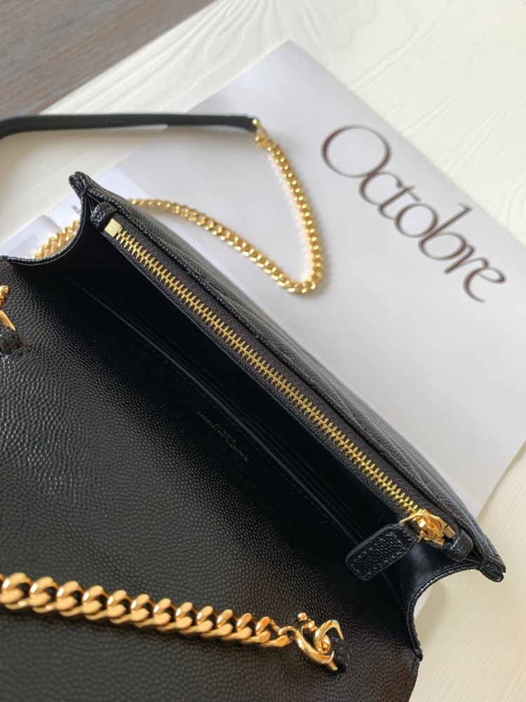 This is the YSL Cassandre chain wallet, crafted from black grained leather with quilted detailing and a gold-tone metal YSL logo on the front. It can be worn as a shoulder or crossbody bag, combining practicality with brand recognition.
