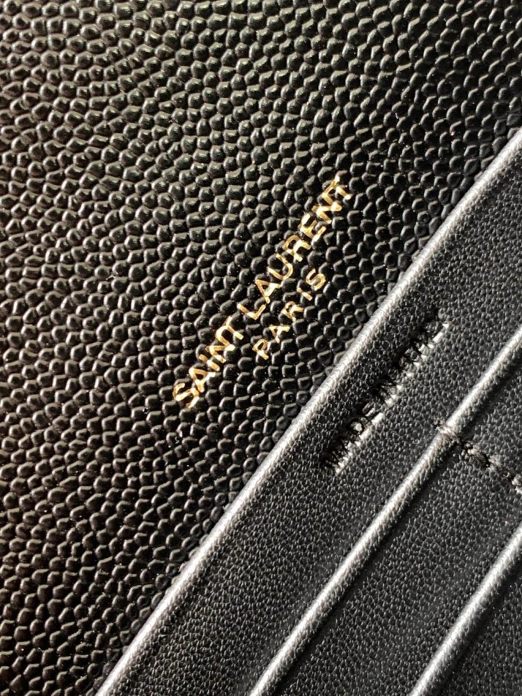 This is the YSL Cassandre chain wallet, crafted from black grained leather with quilted detailing and a gold-tone metal YSL logo on the front. It can be worn as a shoulder or crossbody bag, combining practicality with brand recognition.