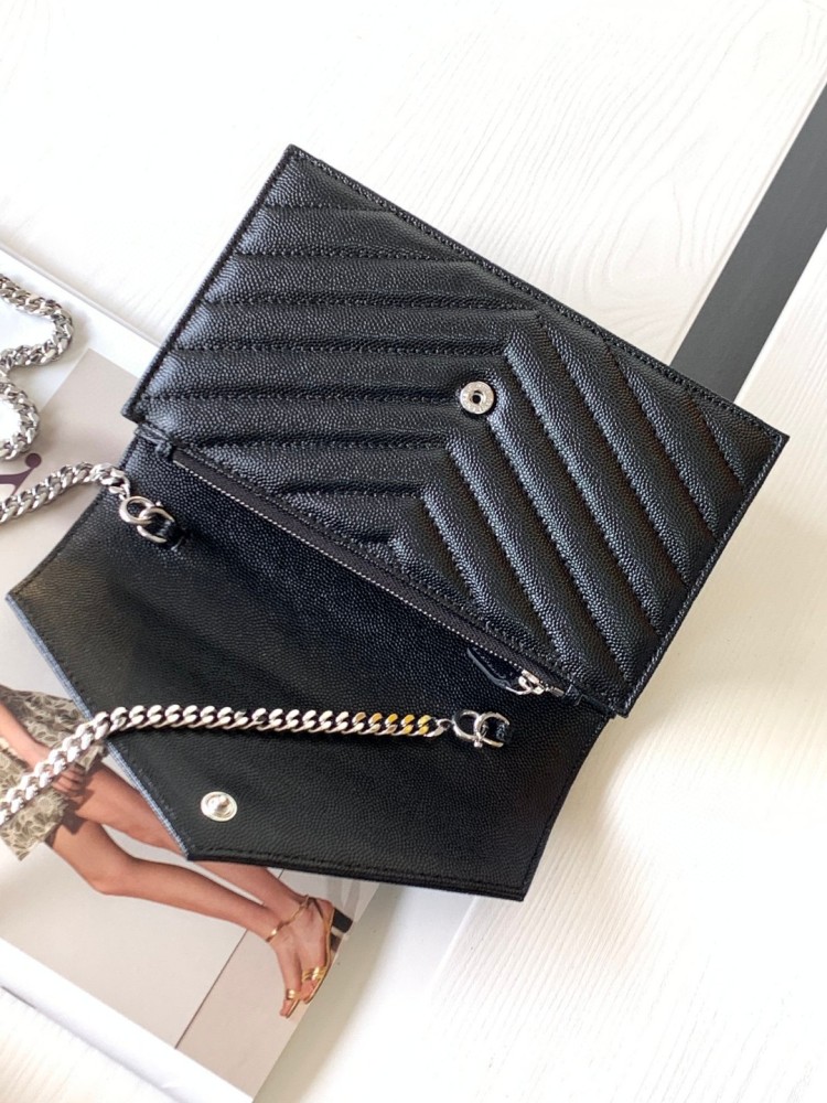 This is the YSL Cassandre chain wallet, crafted from black grained leather with quilted detailing and a silver-tone metal YSL logo on the front. It can be worn as a shoulder or crossbody bag, combining practicality with brand recognition.