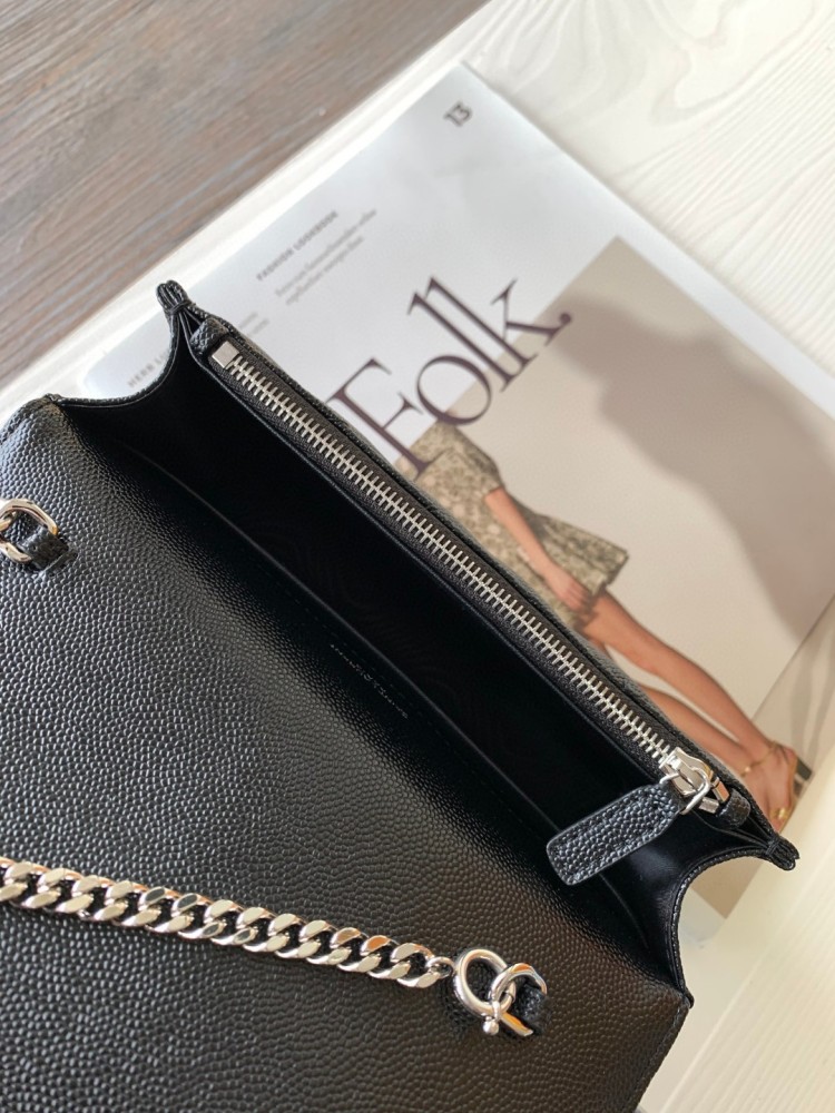 This is the YSL Cassandre chain wallet, crafted from black grained leather with quilted detailing and a silver-tone metal YSL logo on the front. It can be worn as a shoulder or crossbody bag, combining practicality with brand recognition.
