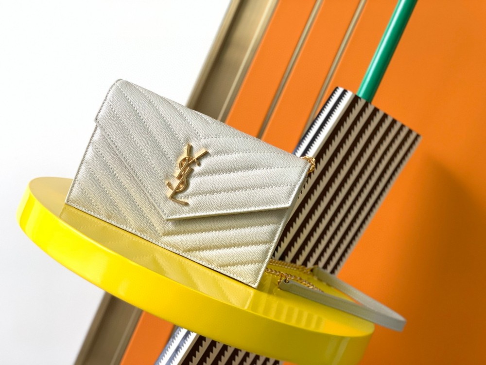 This is the YSL Cassandre chain wallet, crafted from white grained leather with quilted detailing and a gold-tone metal YSL logo on the front. It can be worn as a shoulder or crossbody bag, combining practicality with brand recognition.