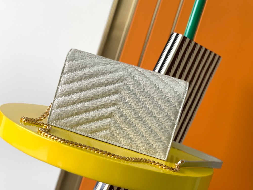 This is the YSL Cassandre chain wallet, crafted from white grained leather with quilted detailing and a gold-tone metal YSL logo on the front. It can be worn as a shoulder or crossbody bag, combining practicality with brand recognition.