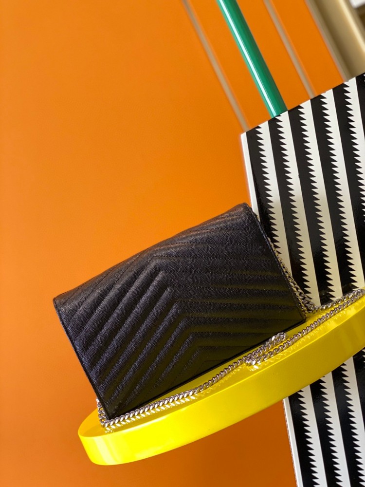 This is the YSL Cassandre chain wallet, crafted from black grained leather with quilted detailing and a silver-tone metal chain, suitable for shoulder or crossbody wear.