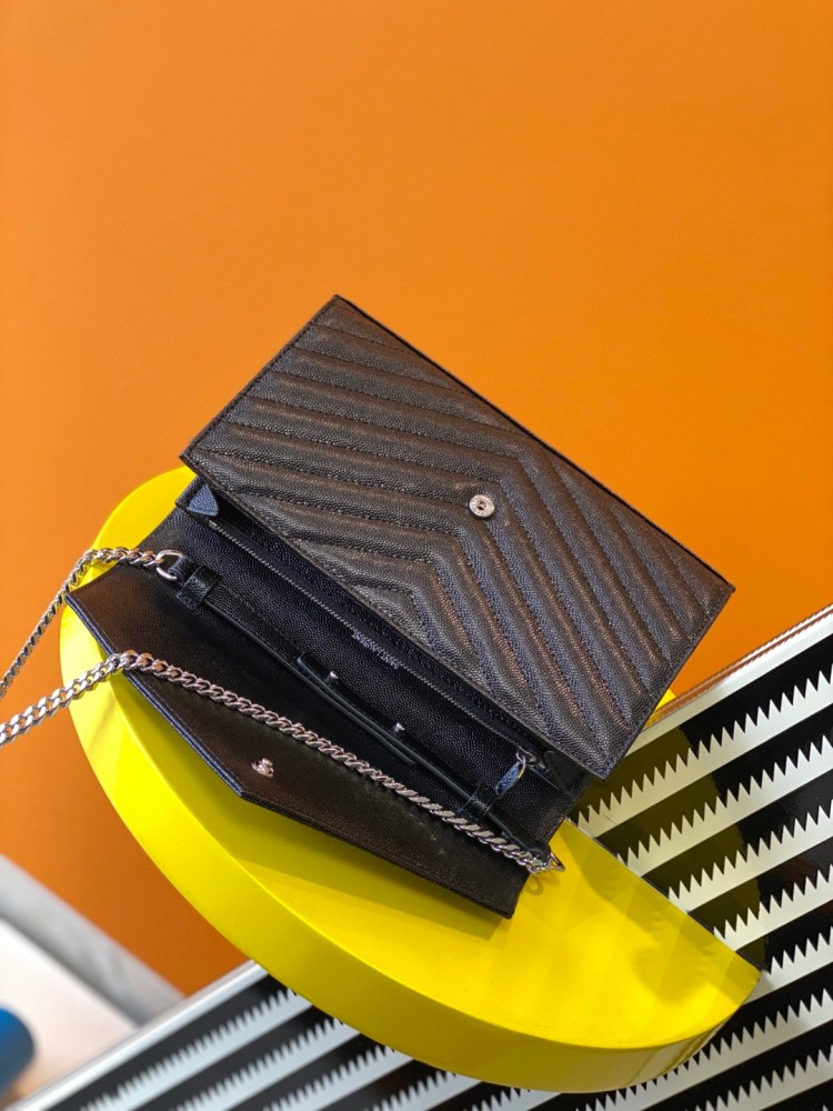 This is the YSL Cassandre chain wallet, crafted from black grained leather with quilted detailing and a silver-tone metal chain, suitable for shoulder or crossbody wear.