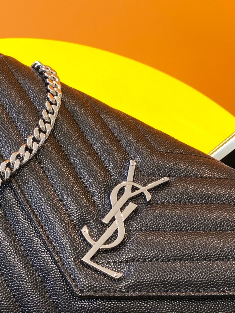 This is the YSL Cassandre chain wallet, crafted from black grained leather with quilted detailing and a silver-tone metal chain, suitable for shoulder or crossbody wear.