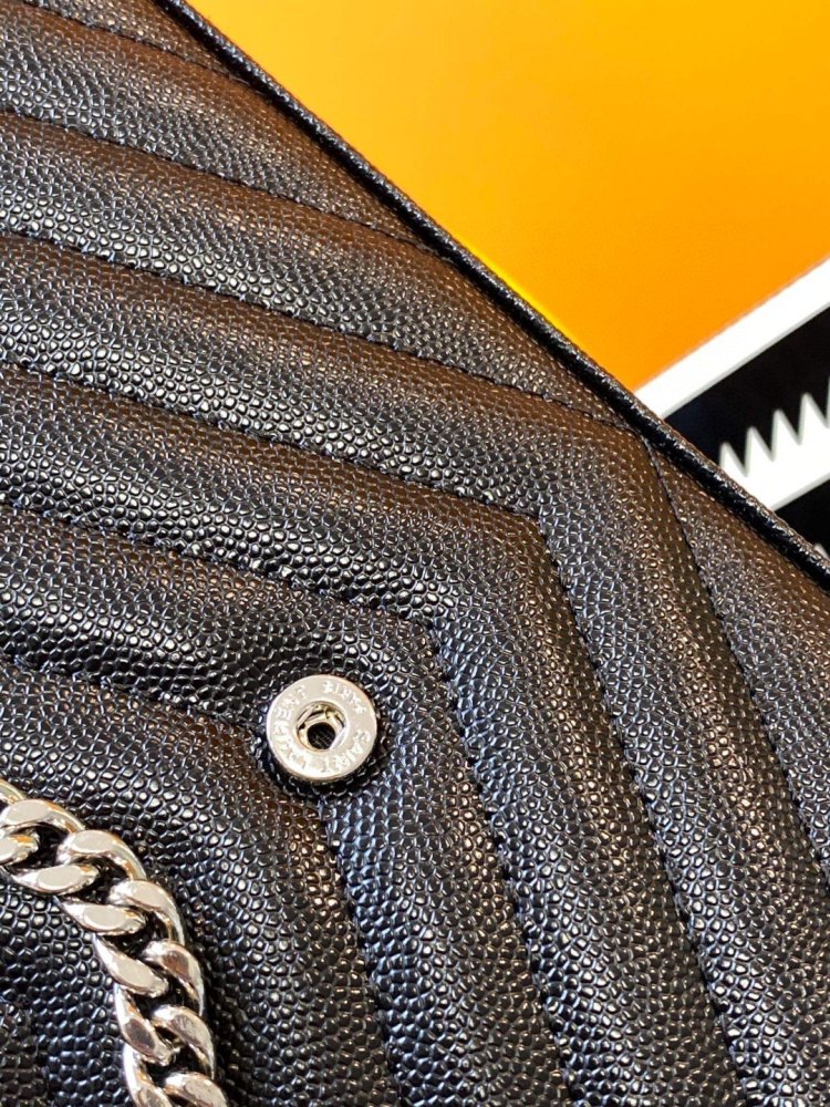 This is the YSL Cassandre chain wallet, crafted from black grained leather with quilted detailing and a silver-tone metal chain, suitable for shoulder or crossbody wear.