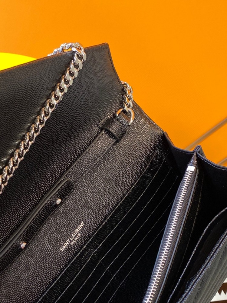 This is the YSL Cassandre chain wallet, crafted from black grained leather with quilted detailing and a silver-tone metal chain, suitable for shoulder or crossbody wear.