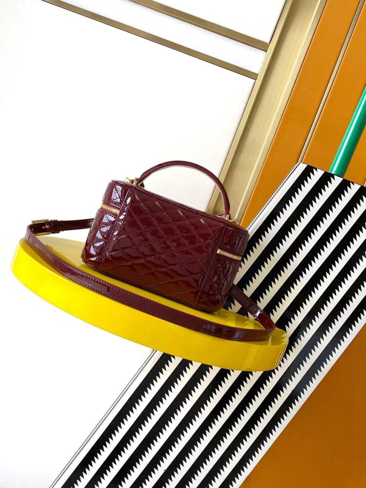 This is the YSL burgundy patent leather vanity bag with quilted stitching, featuring a top handle and crossbody strap.