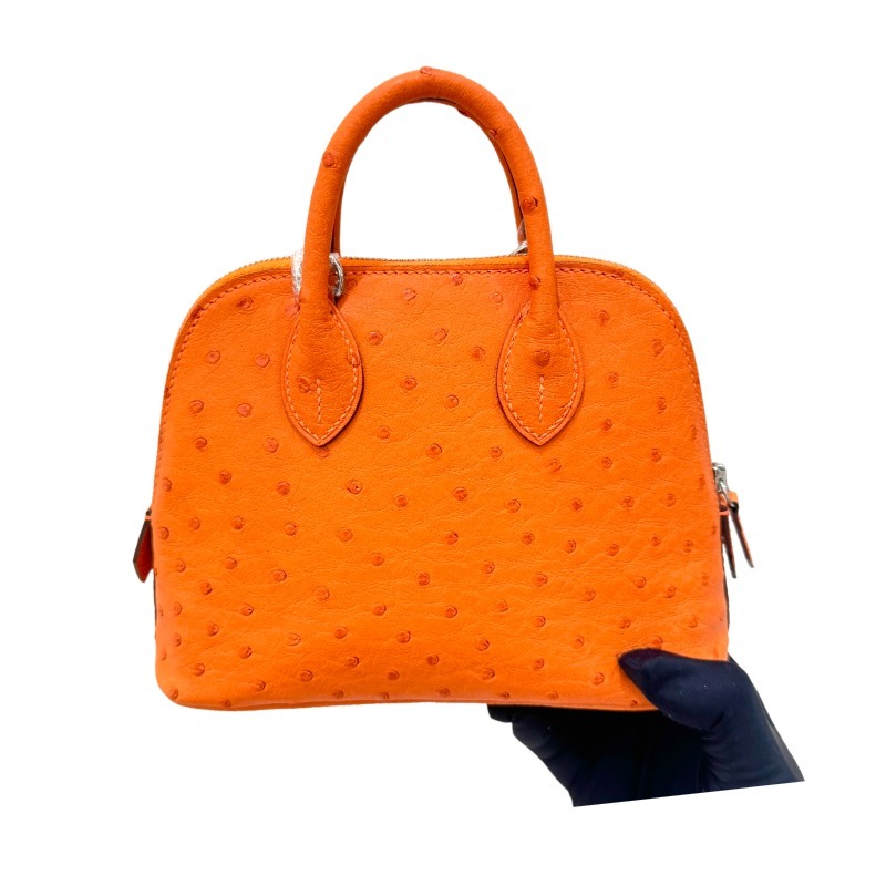 The Hermès Mini Bolide handbag in ostrich leather—featuring the classic Hermès Orange paired with silver hardware—is a highly recognizable and vibrant piece within the brand's exotic skins collection.