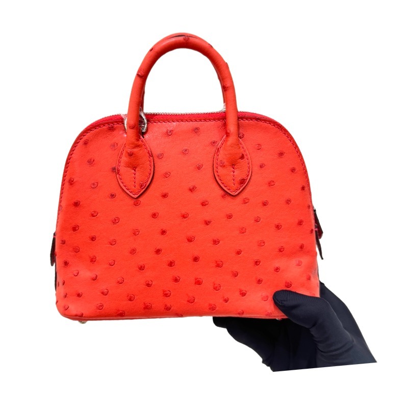 The Hermès Mini Bolide handbag in ostrich leather—featuring a striking Tomato Red (orange-red) hue paired with silver hardware—is a vibrant and highly sought-after piece within the brand's rare skins collection.