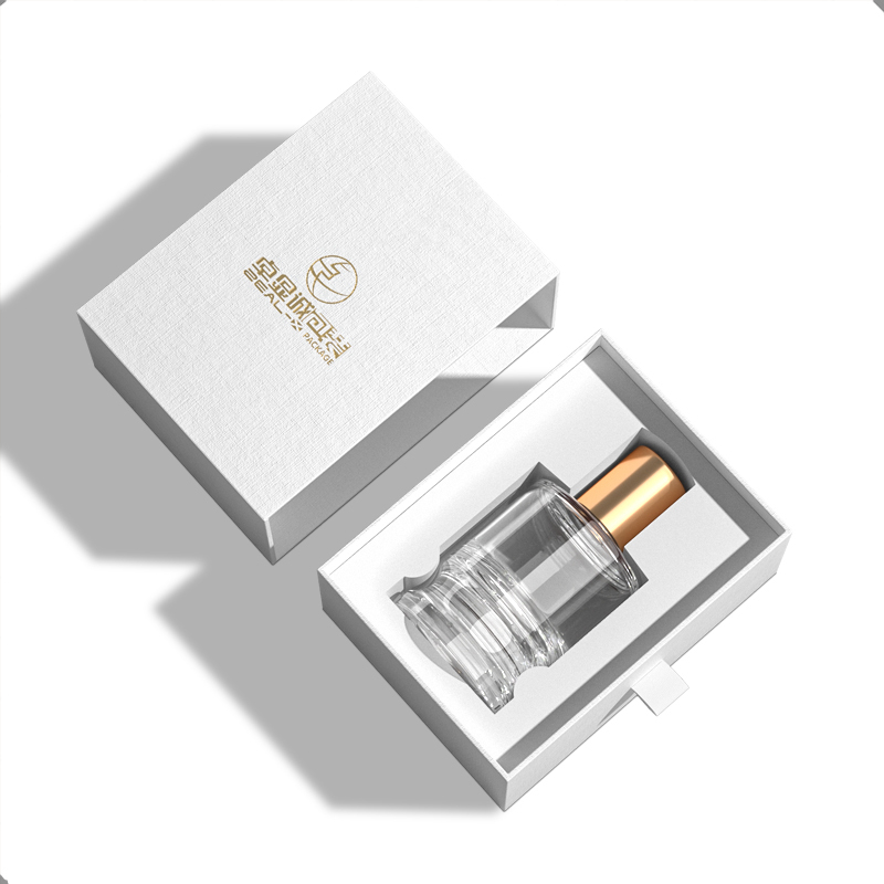 Open white perfume drawer box with a gold-capped perfume bottle in a fitted insert.