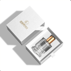 Open white perfume drawer box with a gold-capped perfume bottle in a fitted insert.