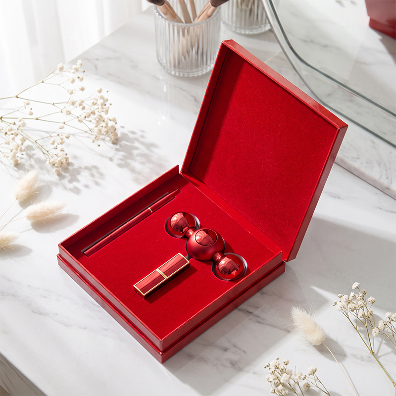 Red cosmetic gift box displaying lip color products in a shaped insert on a marble vanity