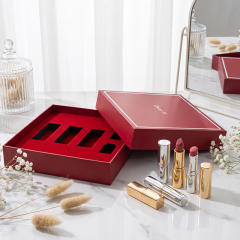 Red lid-and-base makeup gift box with multiple insert compartments displayed beside gold cosmetic tubes