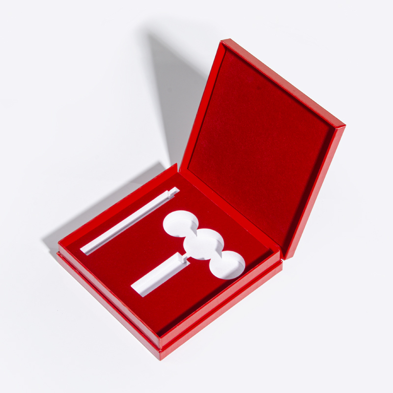 Open red cosmetic presentation box with long rectangular and round insert openings for a coordinated makeup set