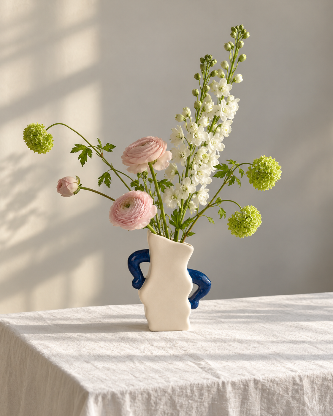 ATW-S252342-A sculptural wave cream and cobalt stoneware floral vessel with botanical arrangement in styled interior