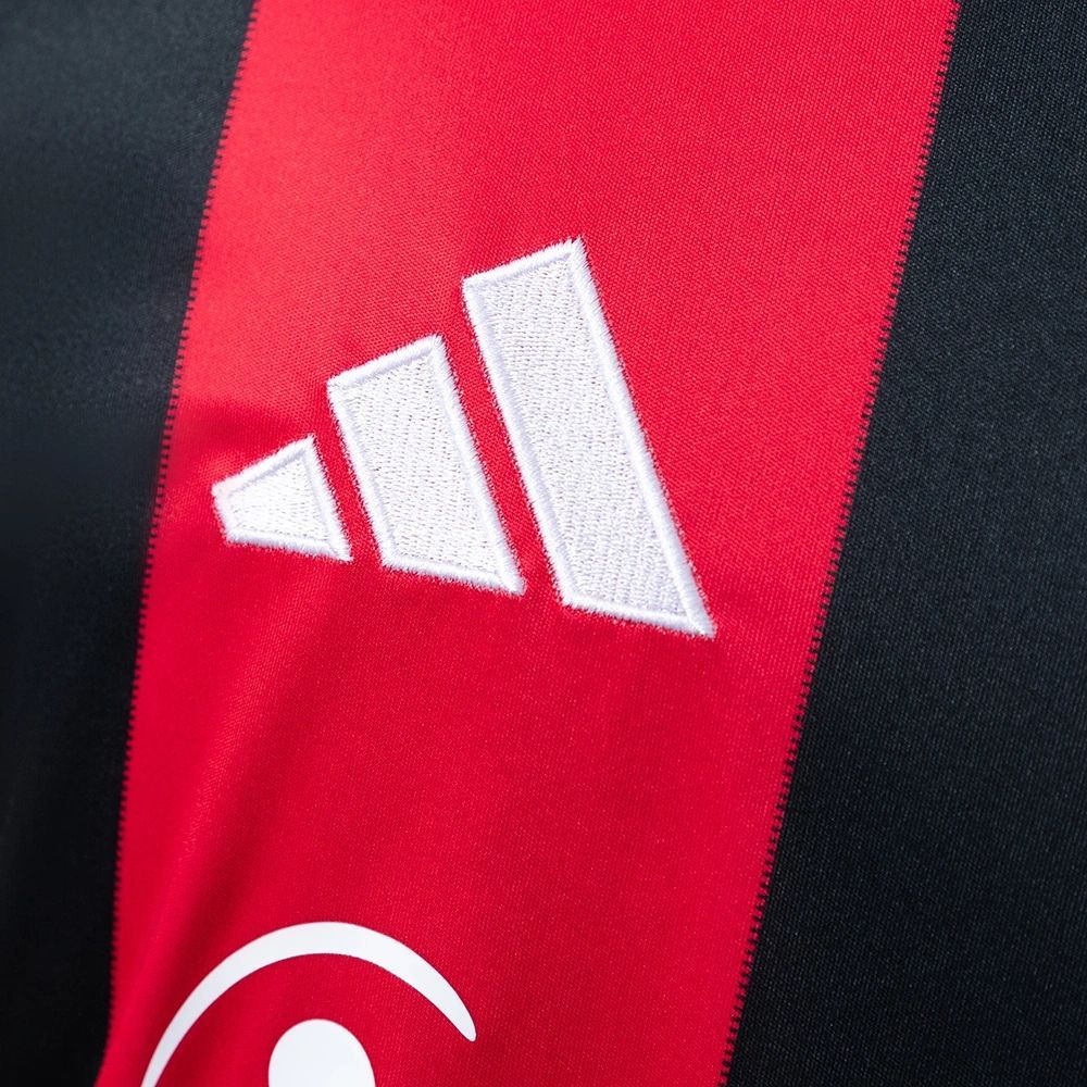 Close-up of the 2025-26 Eintracht Frankfurt home jersey showing the white Adidas logo embroidered on the red and black stripe.