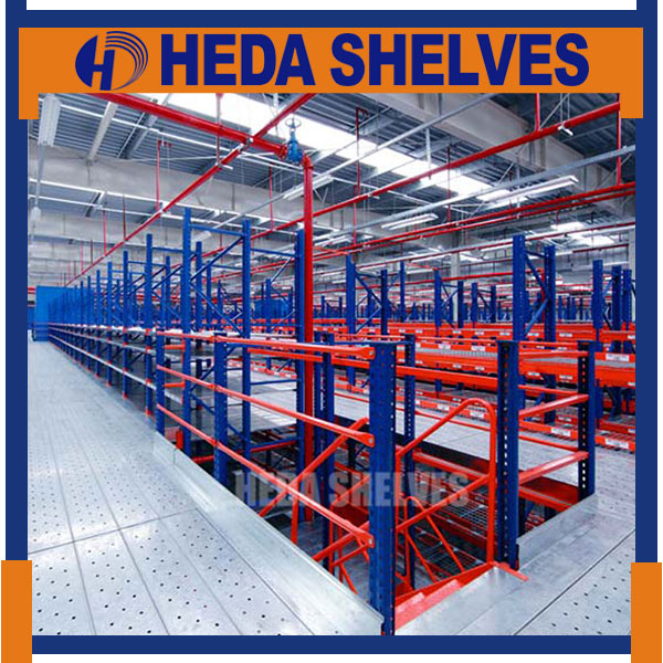 Original HEDA No.00293 industrial multi-level warehouse showing a large silver-grey perforated steel access floor, red-orange safety railings, blue steel rack frames and orange storage beams