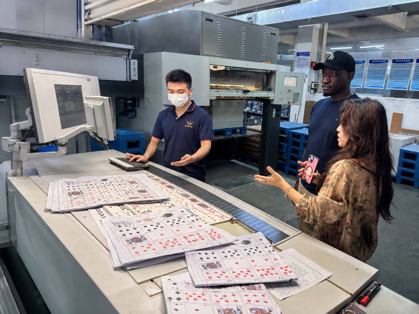 African client and THRIWA team reviewing playing-card printing sheets during a Guangzhou factory visit