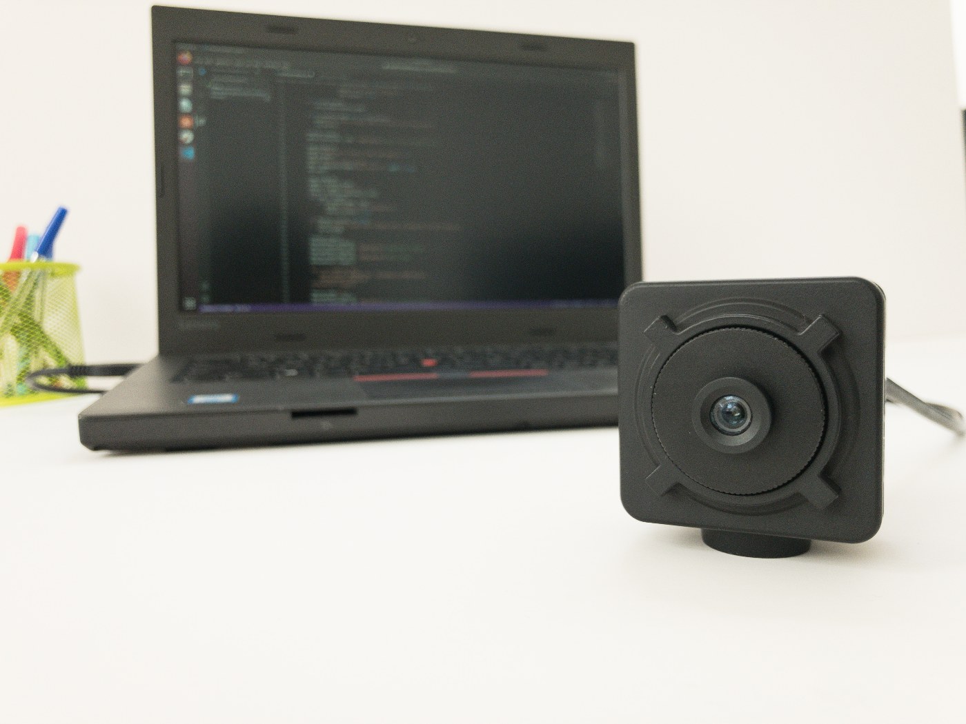 OpenNCC Knight USB AI camera on a desk in front of a laptop running development tools &mdash; AI models run on-board, no host compute required